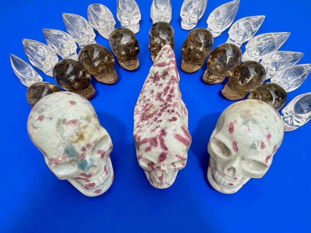 Featured image showing several hand-carved crystal skulls in natural light, including amethyst, quartz, and golden healer, ethically sourced from Brazil.